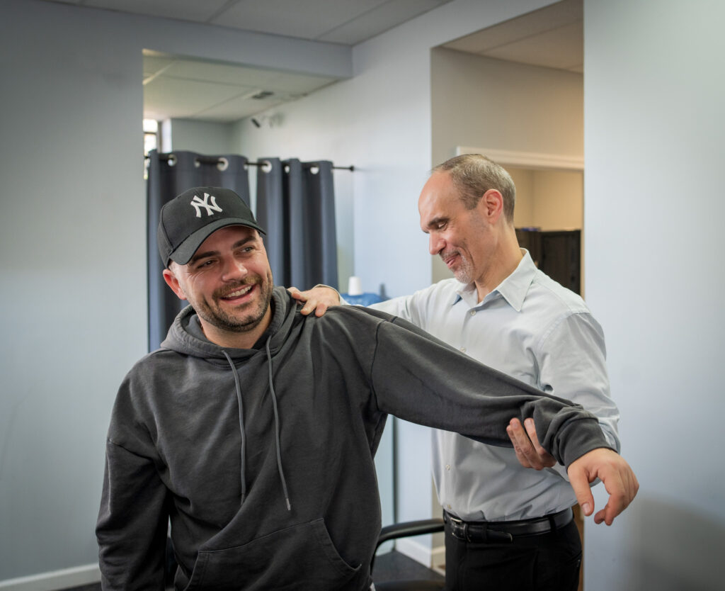 A patient stretches a blue resistance band with assistance from Health and Fitness Team at Health and Fitness Professionals, part of a recovery plan. Consider Health and Fitness Professionals as your car accident chiropractor NJ.