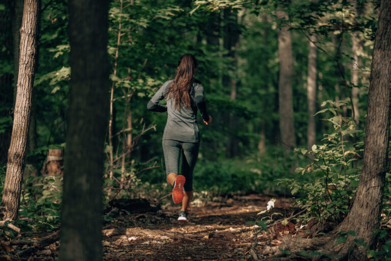 image of a woman trail running in a forest