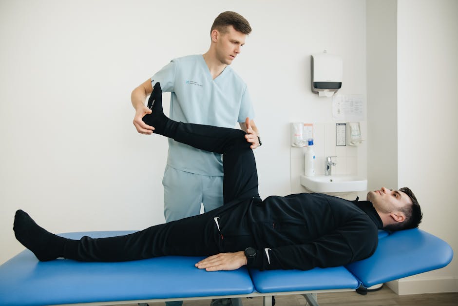 A physical therapist guiding a patient through a hip flexion movement on a treatment table